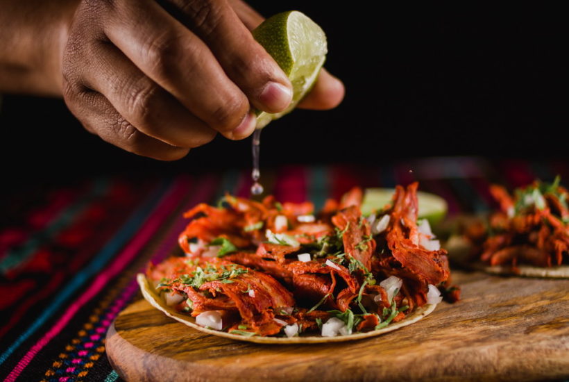 Close up of a Lime Being Squeezed in a Mexican Taco with Traditional Colorful Background Flurl food delivery separates dining out from eating